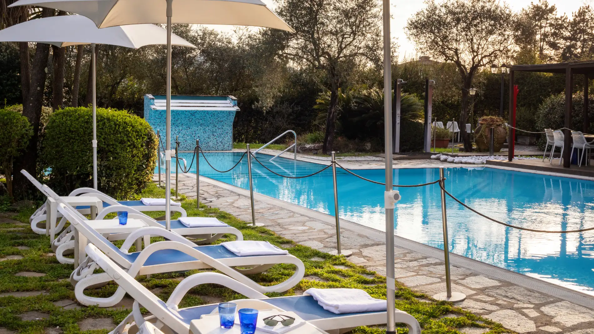 Outdoor swimming pool surrounded by greenery with sun loungers and umbrellas for open-air relaxation in Liguria - Sarzana Park Hotel, BZAR hotels in Liguria