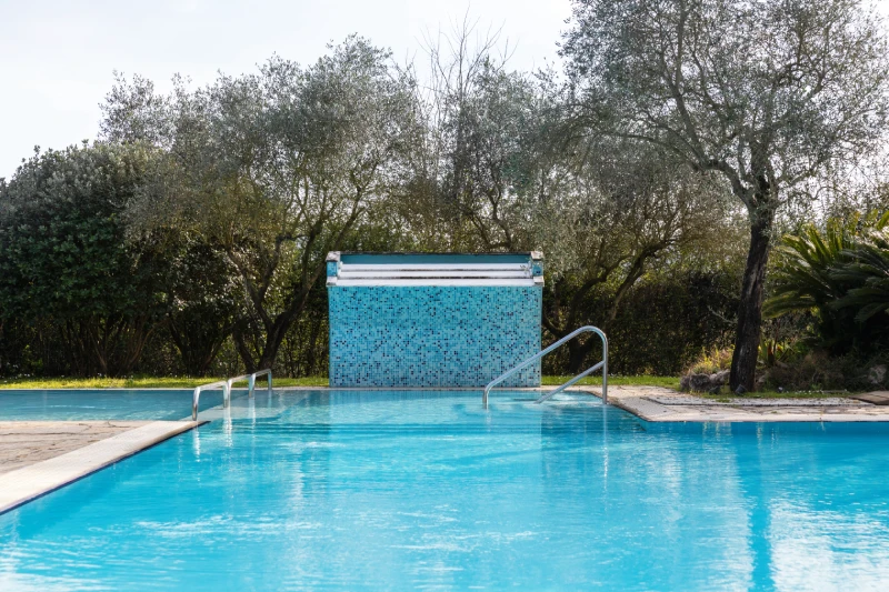 Outdoor swimming pool surrounded by greenery with waterfall and hydromassage area for open-air relaxation in Sarzana, Liguria - Sarzana Park Hotel, BZAR hotels in Liguria