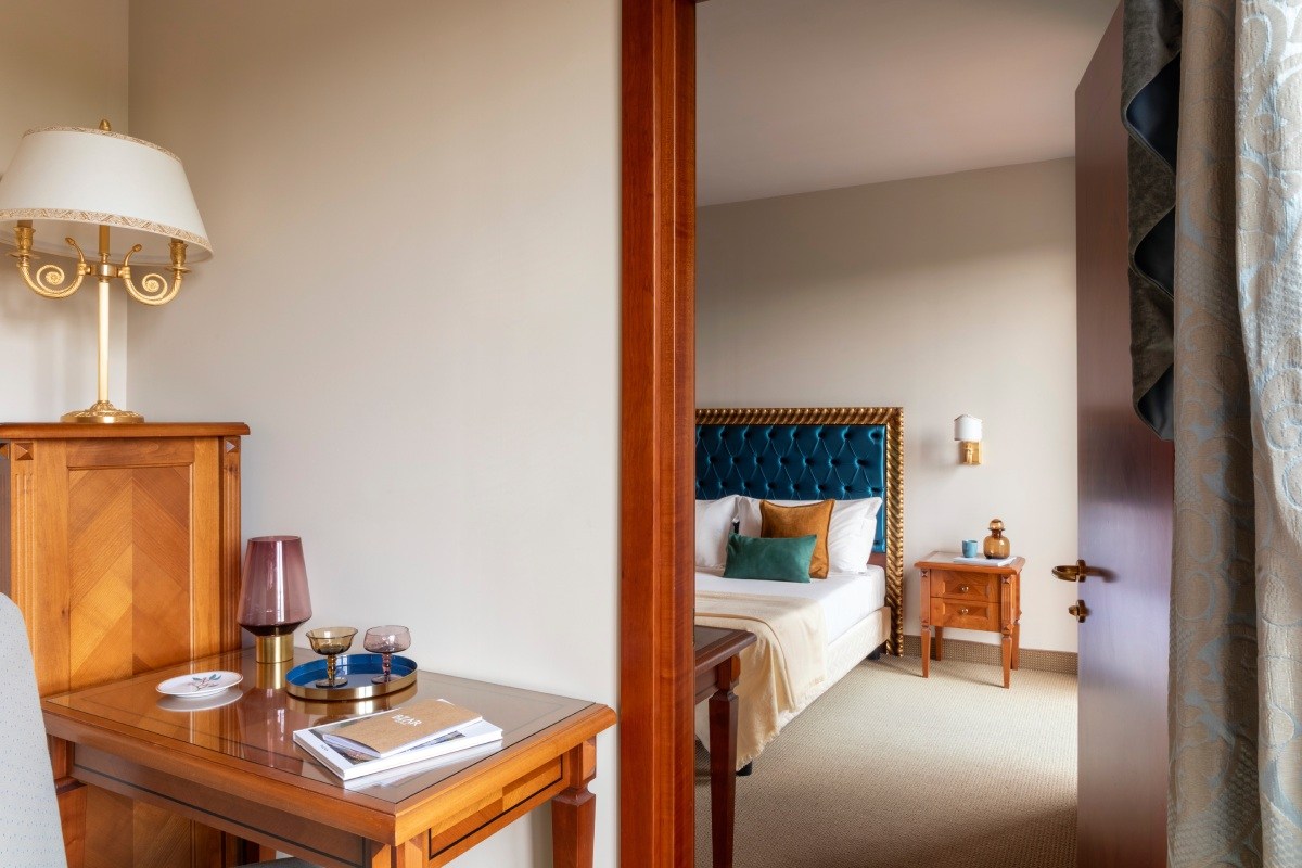 Room entrance with desk area, view into bedroom with blue headboard and classic details for a Liguria stay - Sarzana Park Hotel, BZAR hotels in Liguria