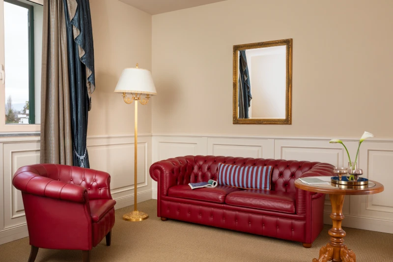 Living area with red leather sofas and side table, an elegant setting for a premium stay in Sarzana, Liguria - Sarzana Park Hotel, BZAR hotels in Liguria